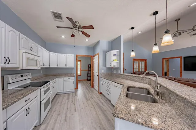 a large kitchen with stainless steel appliances granite countertop a sink stove and refrigerator