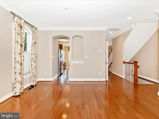 a view of an empty room with window and wooden floor