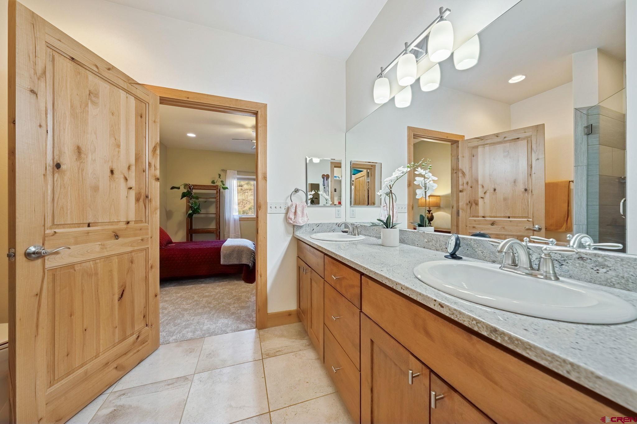 67 Mountain Stream Court Durango, CO 81301 - Photo 25 of 35 a spacious bathroom with a granite countertop sink a mirror and a shower
