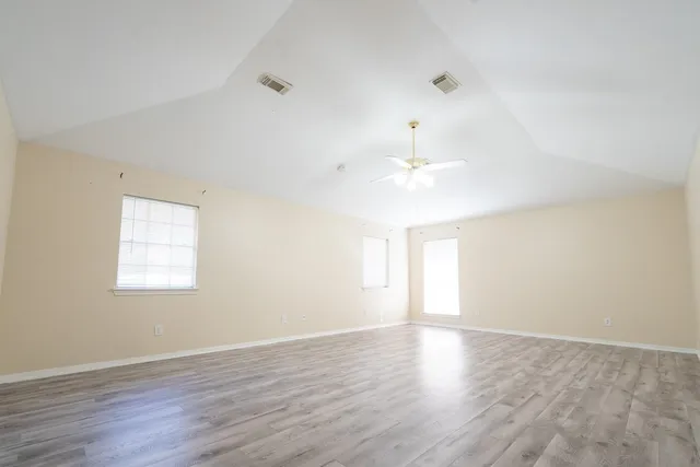 an empty room with wooden floor and windows