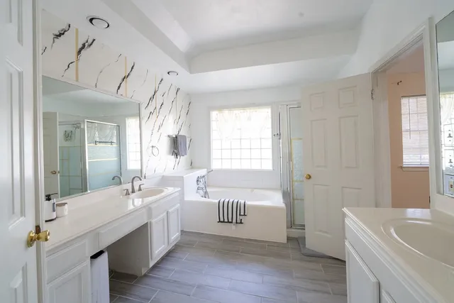 a bathroom with a double vanity sink a mirror and a bathtub