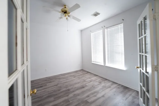 a view of an empty room with a window and wooden floor