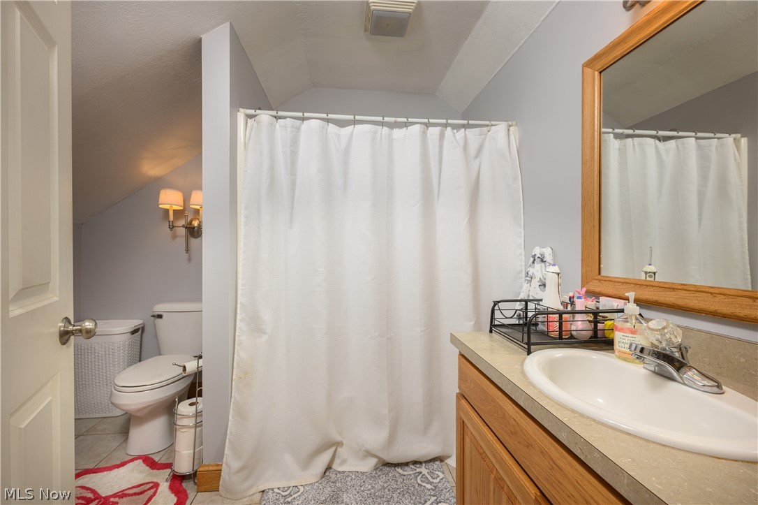 806 Forrest Ridge Drive Dover, OH 44622 - Photo 30 of 36 Full bath featuring vanity, a shower with curtain, vaulted ceiling, and light tile patterned floors
