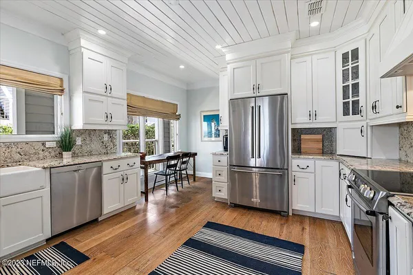 a kitchen with granite countertop a refrigerator stove microwave and cabinets