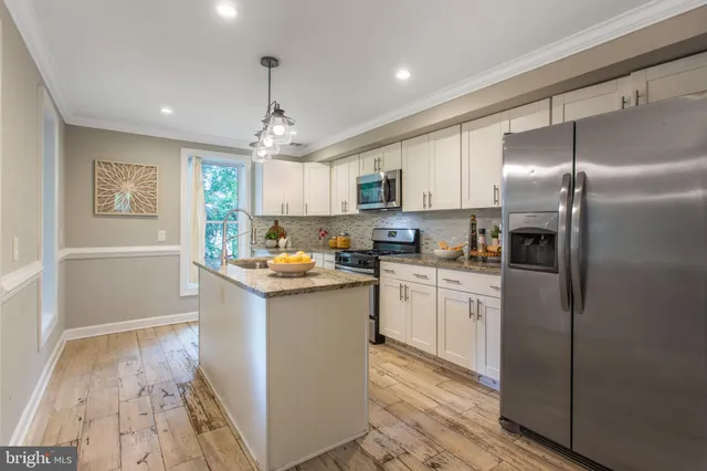 a kitchen with kitchen island granite countertop appliances cabinets and a sink