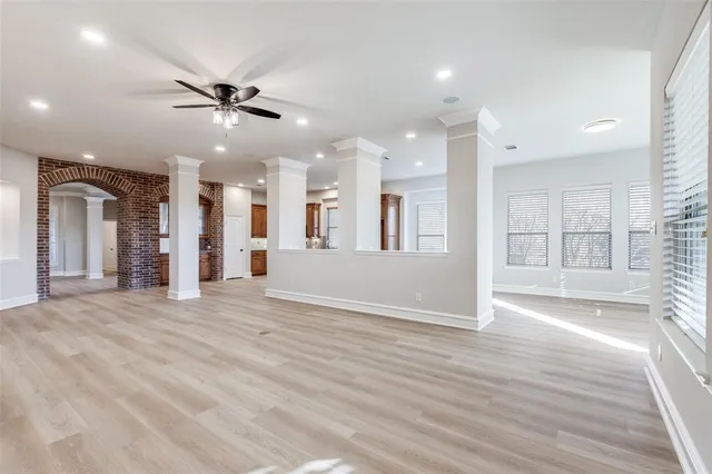 an empty room with wooden floor fireplace and windows