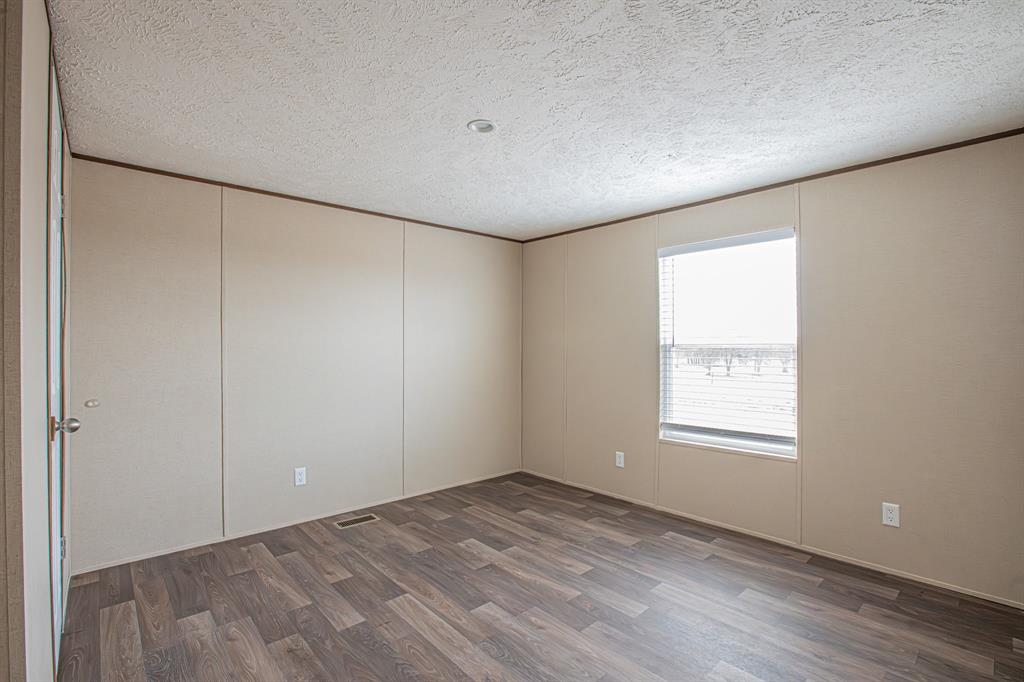 150 Leech Road Poolville, TX 76487 - Photo 21 of 34 a view of an empty room with wooden floor and a window