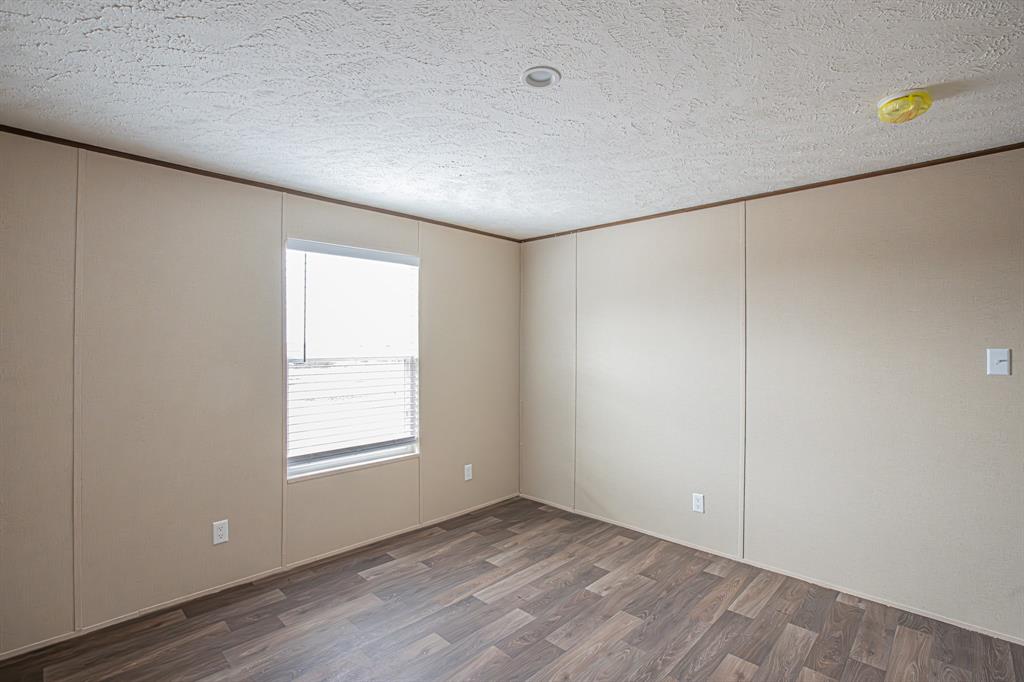 150 Leech Road Poolville, TX 76487 - Photo 22 of 34 a view of an empty room with wooden floor and a window