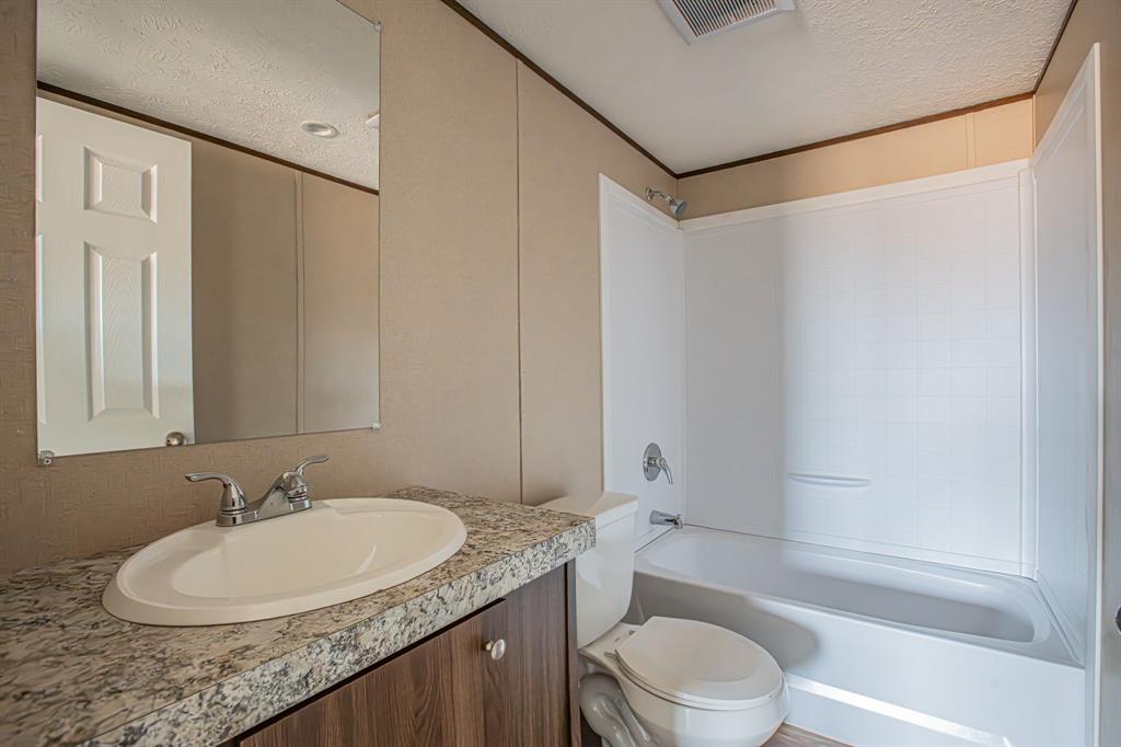 150 Leech Road Poolville, TX 76487 - Photo 25 of 34 a bathroom with a granite countertop sink toilet and shower
