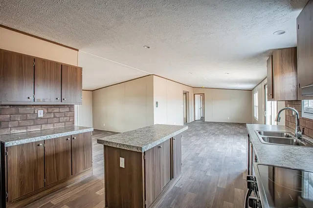 a kitchen with granite countertop a sink stove and cabinets