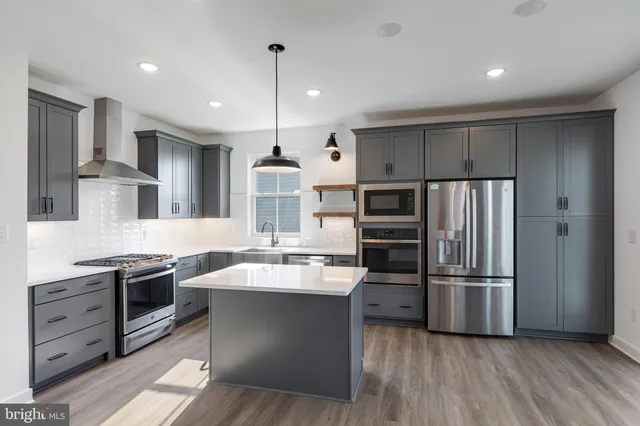 a large kitchen with stainless steel appliances kitchen island granite countertop a refrigerator a sink and a stove