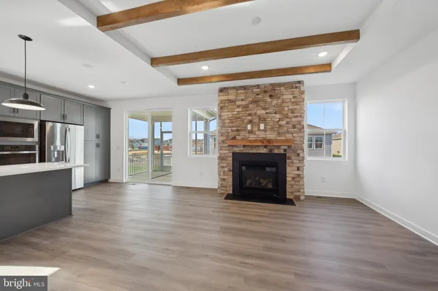 an empty room with wooden floor fireplace and windows