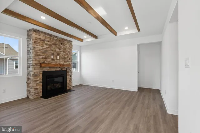 an empty room with wooden floor fireplace and windows