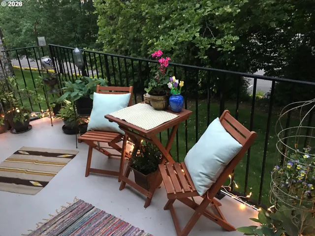 a balcony with wooden floor table and chairs
