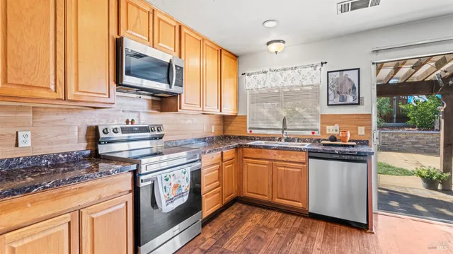 a kitchen with stainless steel appliances granite countertop a stove a sink and a microwave