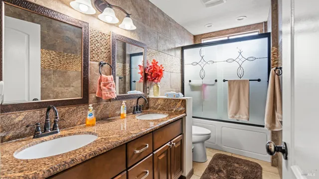 a bathroom with a granite countertop sink mirror vanity and toilet