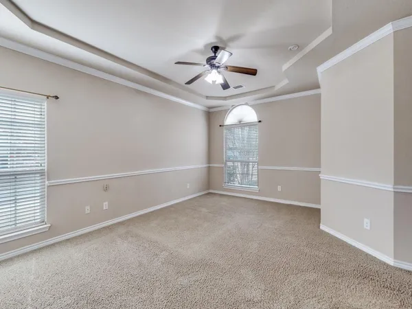 an empty room with windows and fan