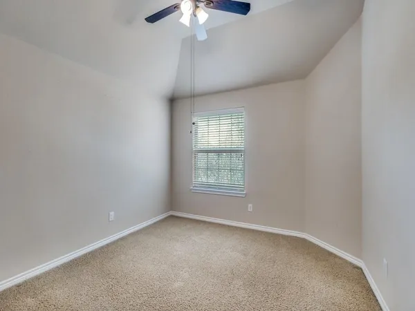 an empty room with a chandelier fan and windows