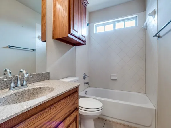 a bathroom with a granite countertop sink a toilet a mirror and bathtub