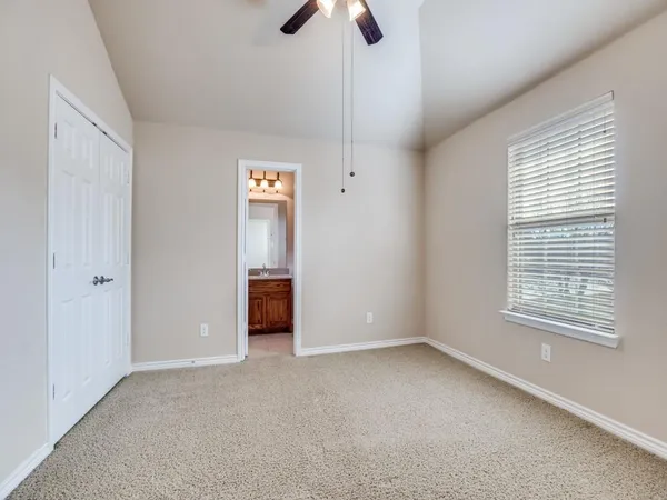 a view of an empty room with window and chandelier fan