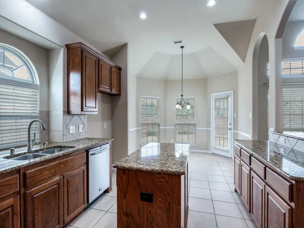 a kitchen with granite countertop kitchen island stainless steel appliances a sink stove and cabinets