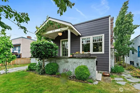 a front view of a house with a yard and potted plants