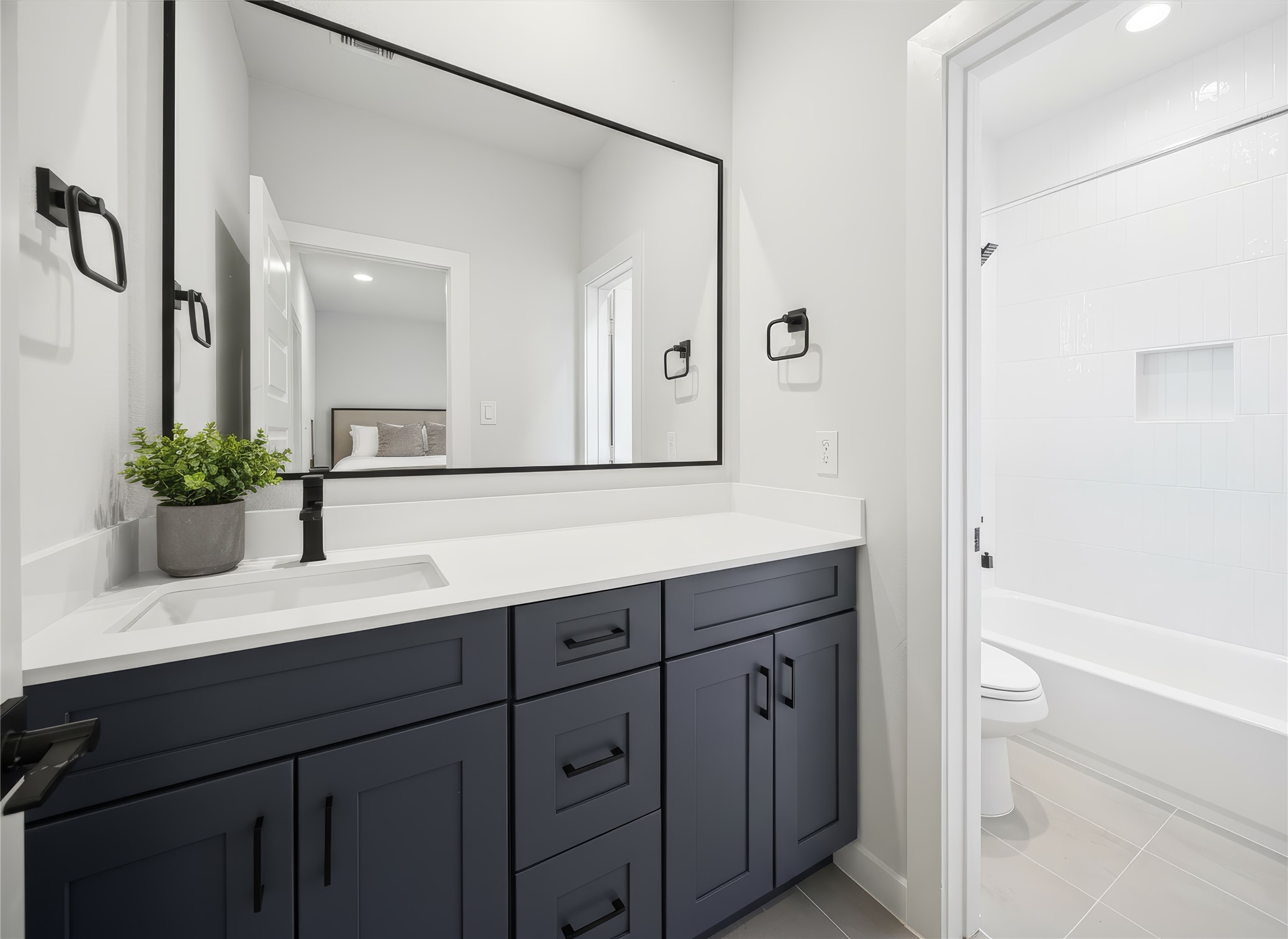 817 Thornton Road, Unit G Houston, TX 77018 - Photo 14 of 49 Third floor bathroom featuring a quartz-topped vanity, matte black fixtures, and a tub-shower combo with bright white tile for a modern, spa-inspired finish. *Virtually staged*
