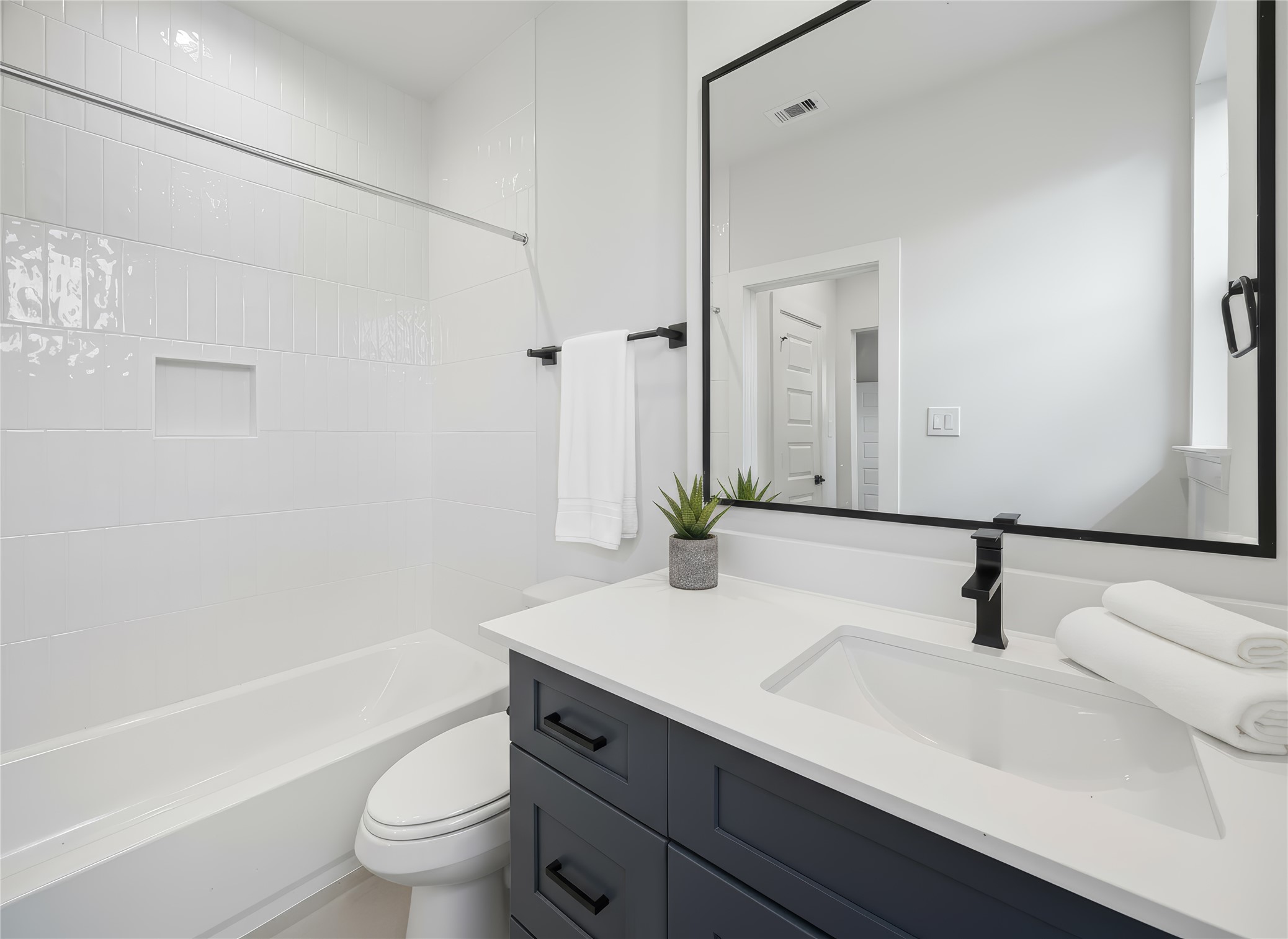 817 Thornton Road, Unit G Houston, TX 77018 - Photo 6 of 49 Ensuite bathroom featuring a quartz-topped vanity, matte black fixtures, and a tub-shower combo. *Virtually staged*