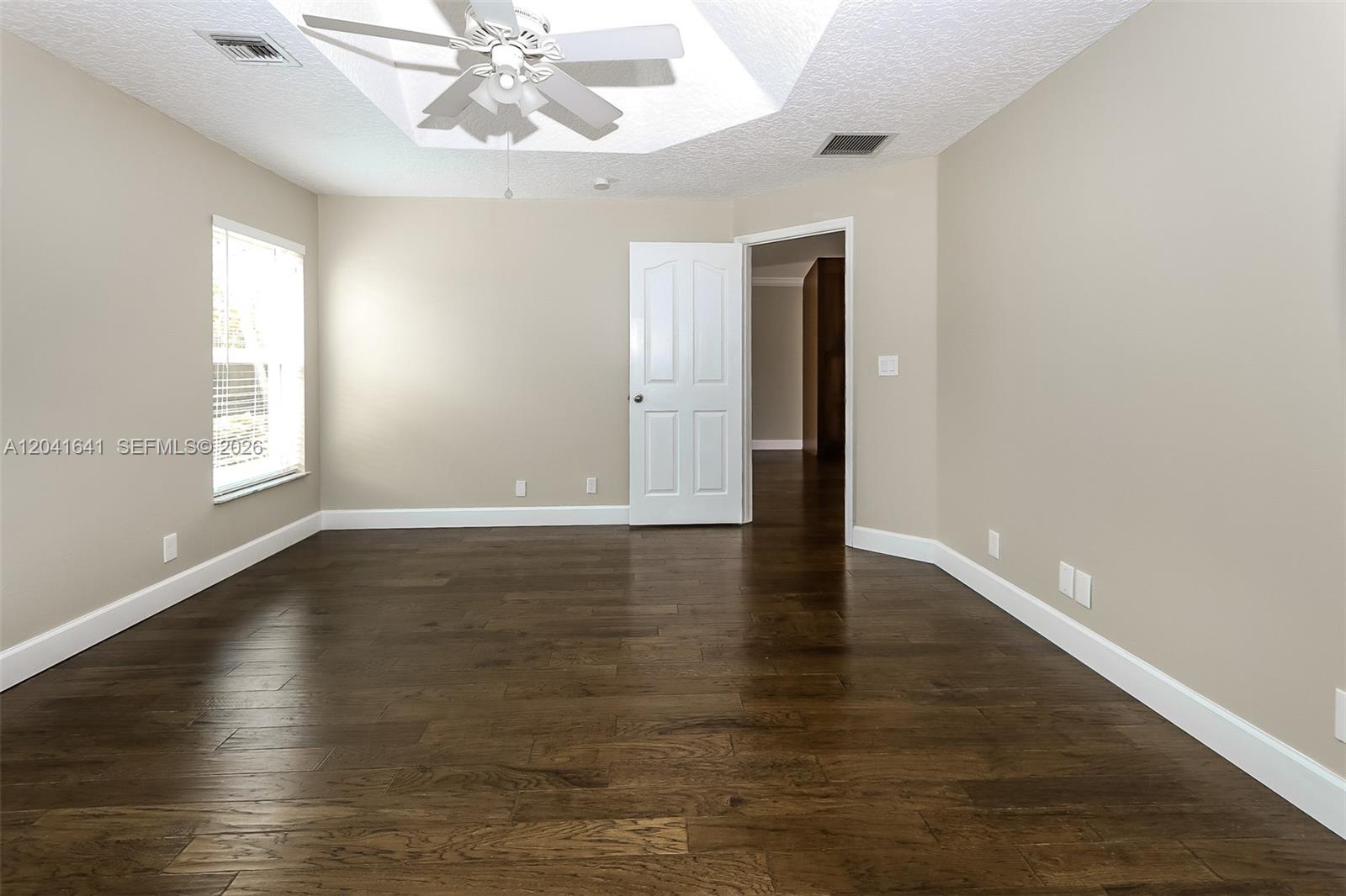 6484 Robinson Street Jupiter, FL 33458 - Photo 7 of 15 an empty room with wooden floor chandelier fan and windows