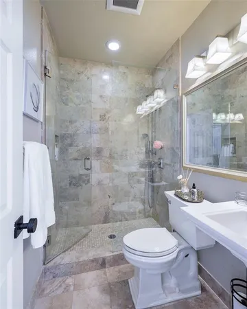 a bathroom with a granite countertop sink a toilet and shower