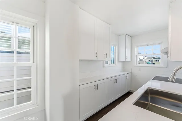 a kitchen with white cabinets and sink