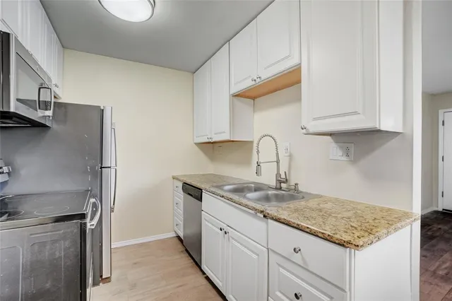 a kitchen with granite countertop a sink stainless steel appliances and cabinets