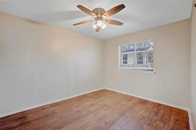 a view of an empty room with window and wooden floor