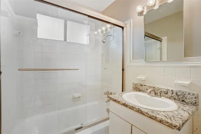 a bathroom with a granite countertop sink mirror toilet and bathtub