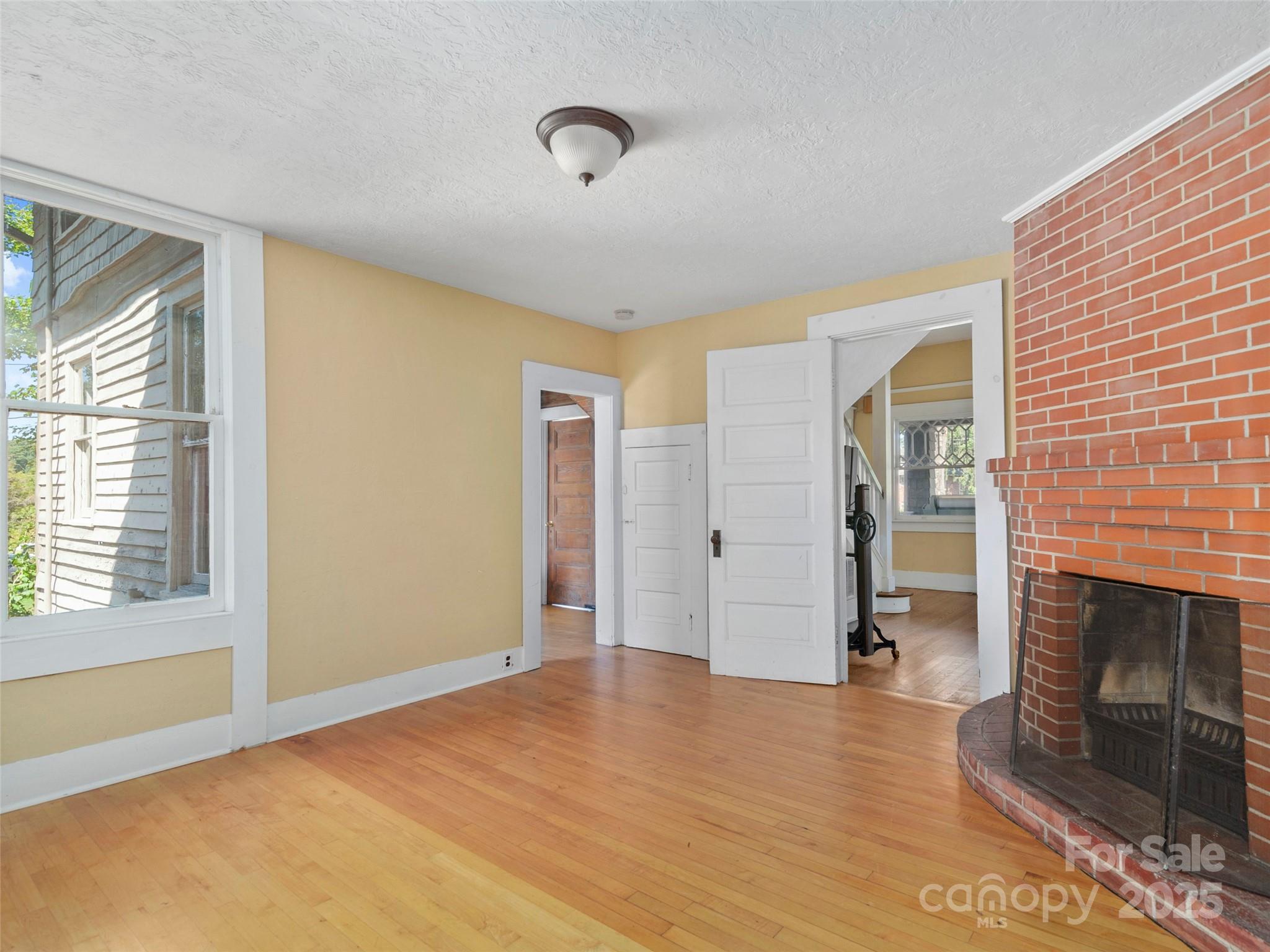 99 Walnut Street Waynesville, NC 28786 - Photo 12 of 34 a view of empty room with wooden floor and fireplace