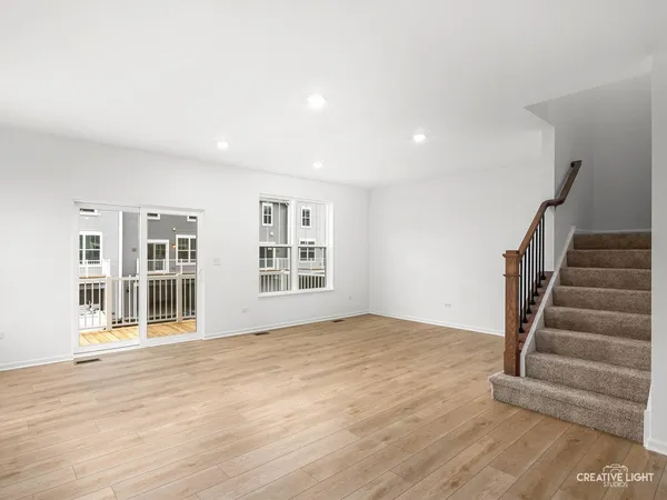a view of an empty room with wooden floor and stairs