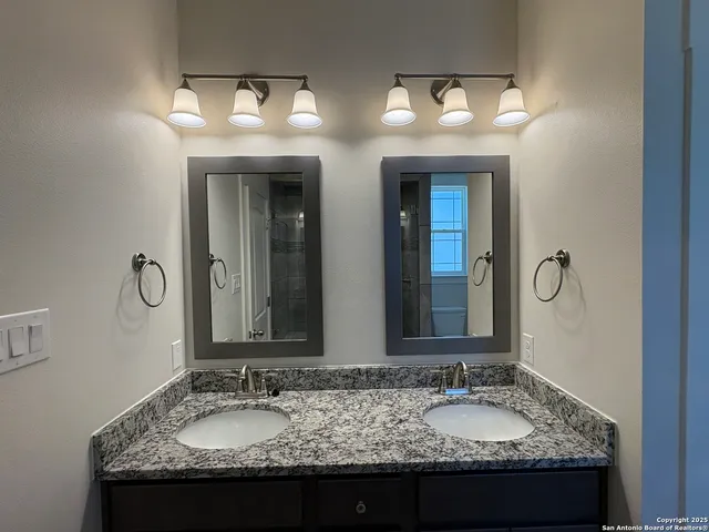 a bathroom with a granite countertop sink double and mirror