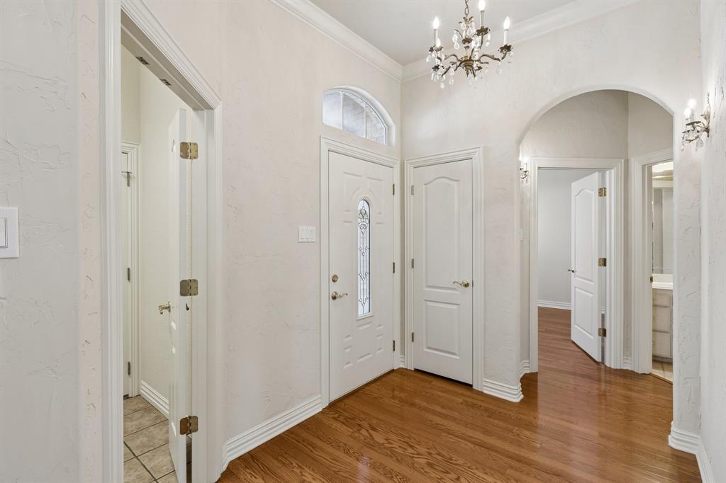 1727 Ridgecrest Drive Cleburne, TX 76033 - Photo 5 of 32 Wood-finish flooring, an arched entryway, decorative wall sconces, a transom window, and a chandelier