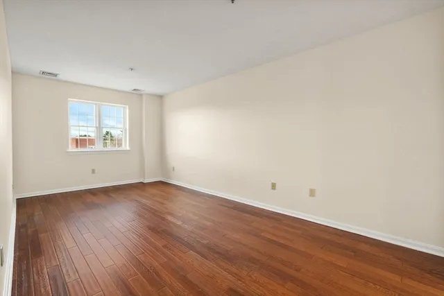 an empty room with wooden floor and window