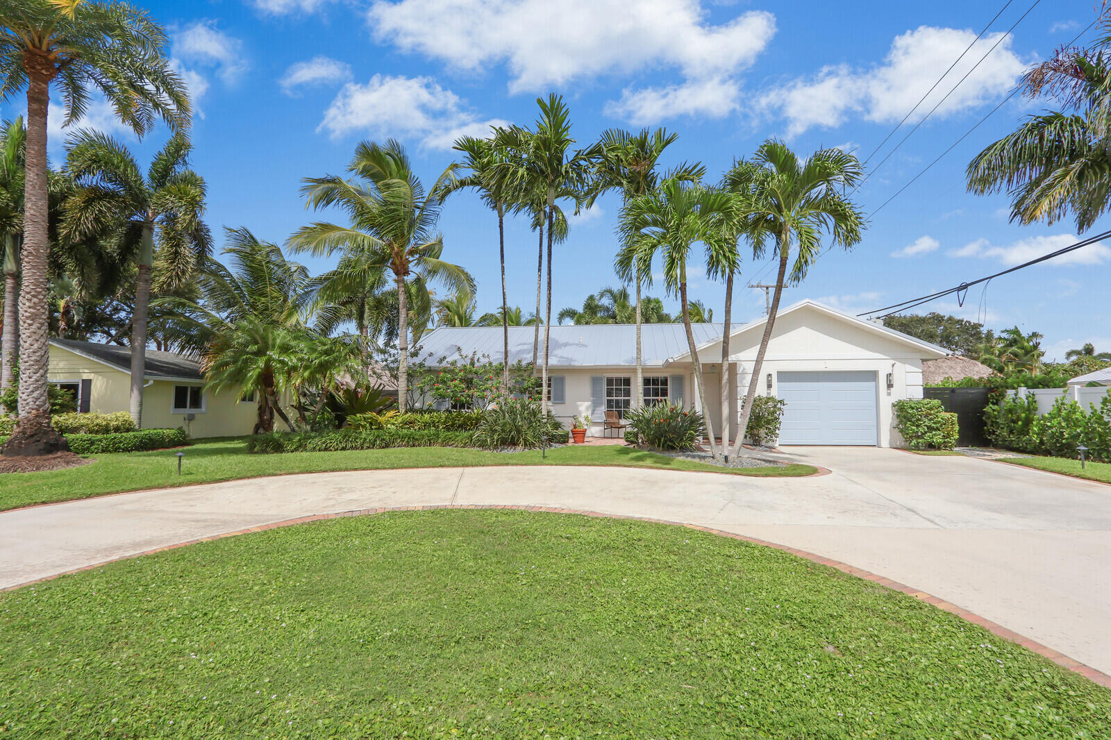 a front view of a house with a garden and palm trees