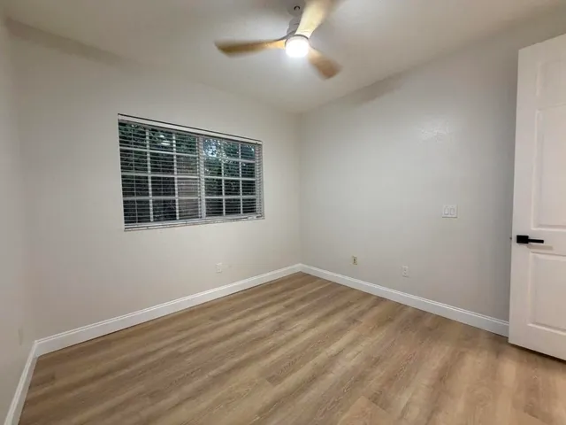 a view of empty room with wooden floor and fan