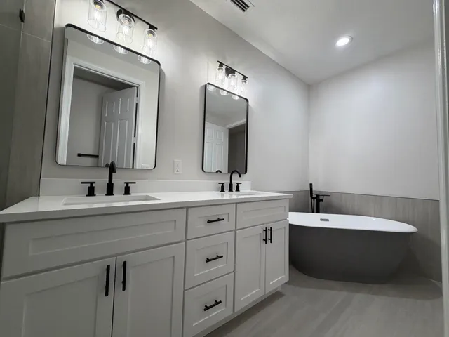 a bathroom with a double vanity sink mirror and bathtub