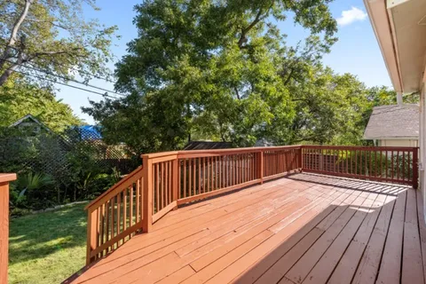 a balcony with wooden floor and trees in the back