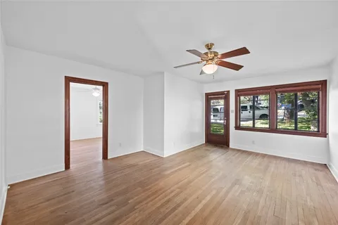 a view of an empty room with window and wooden floor
