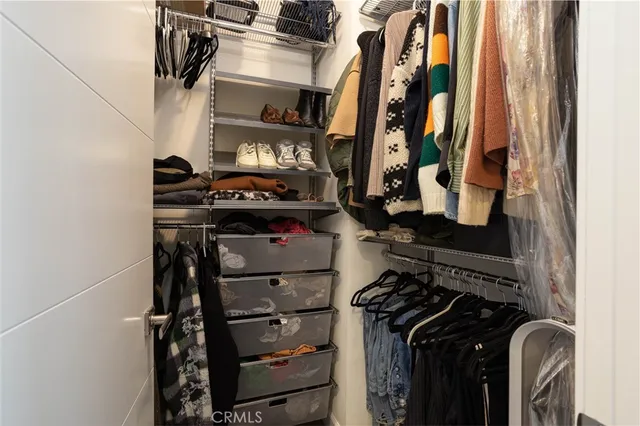 a view of walk in closet with clothes and shoes