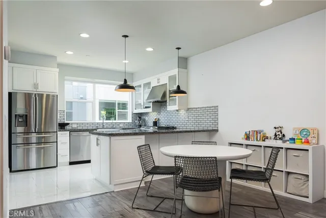 a kitchen with stainless steel appliances granite countertop a table chairs stove and refrigerator