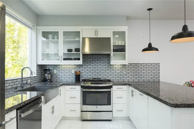 a kitchen with granite countertop a sink a stove and cabinets