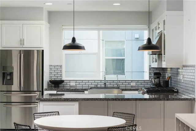 a kitchen with stainless steel appliances a sink a stove a refrigerator and cabinets