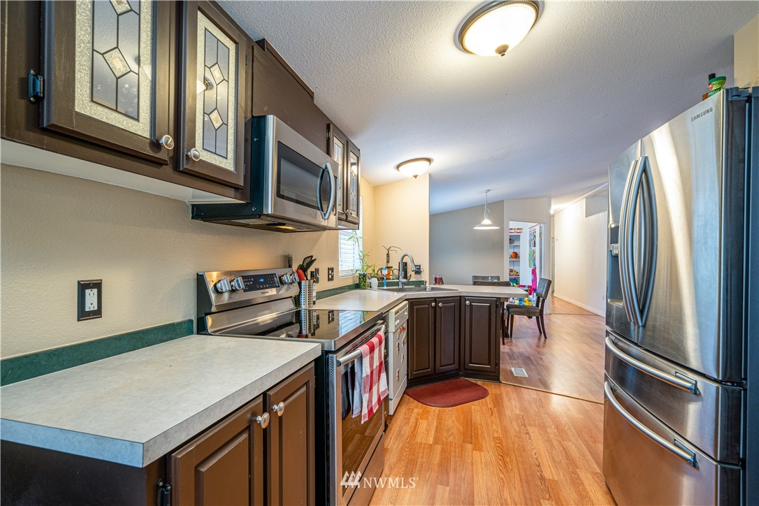 25 Caudill Road Omak, WA 98841 - Photo 7 of 40 a kitchen with stainless steel appliances granite countertop a refrigerator a stove top oven a sink dishwasher and wooden cabinets with wooden floor