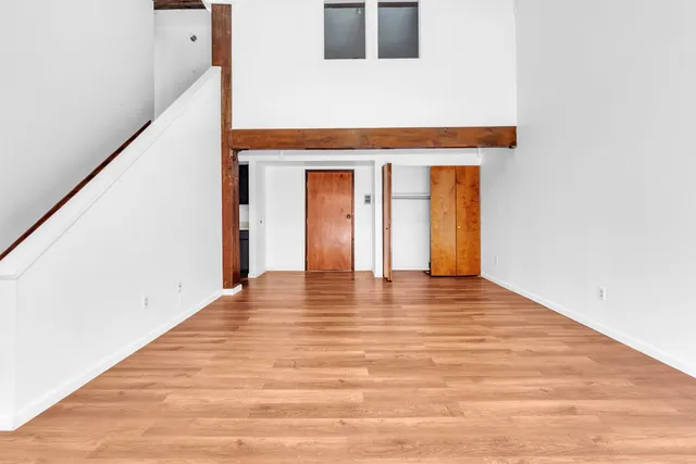 a view of an empty room with wooden floor and a window